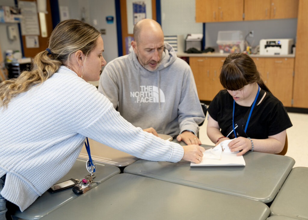 teacher with two students looking at a notebook