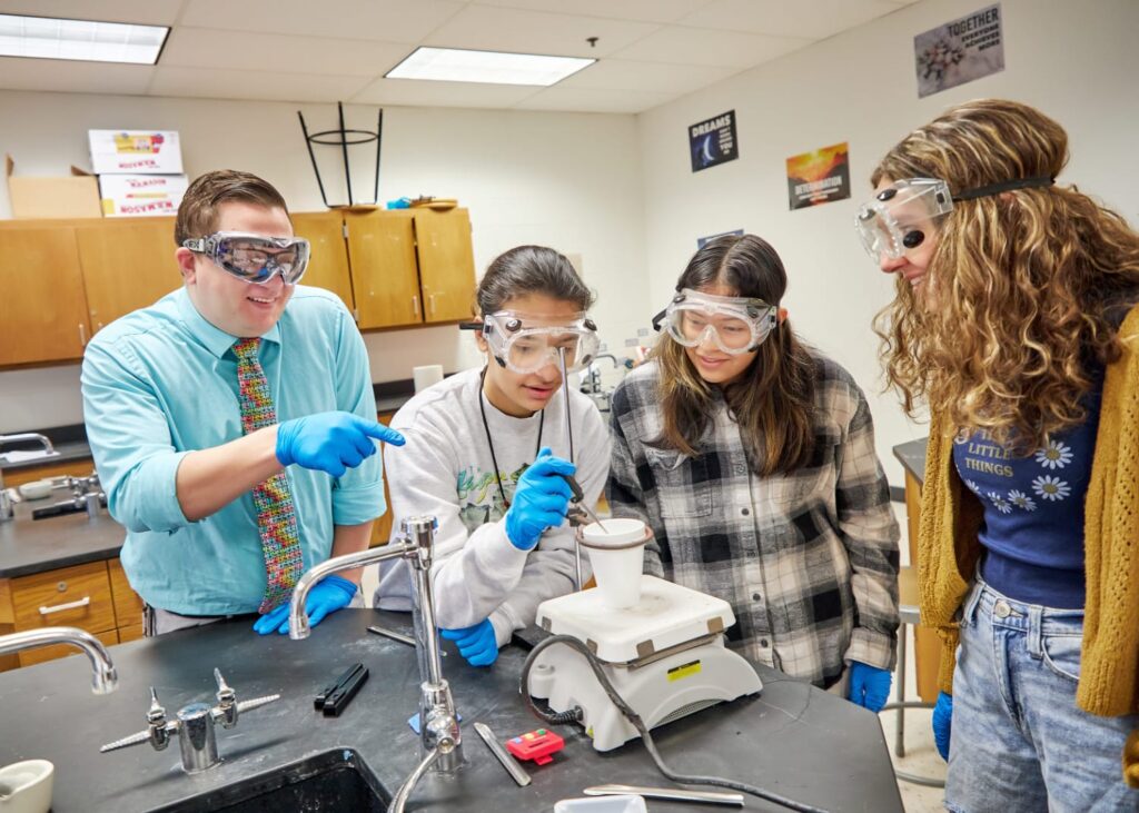 Students and teacher in lab, wearing safety goggles