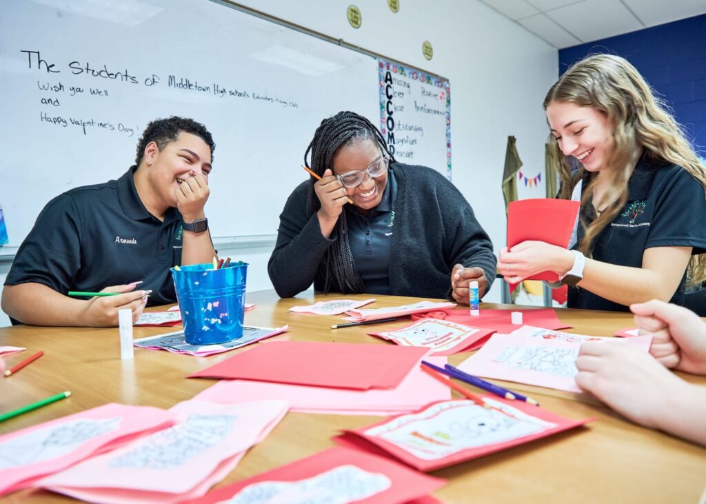 Three students at a table smiling