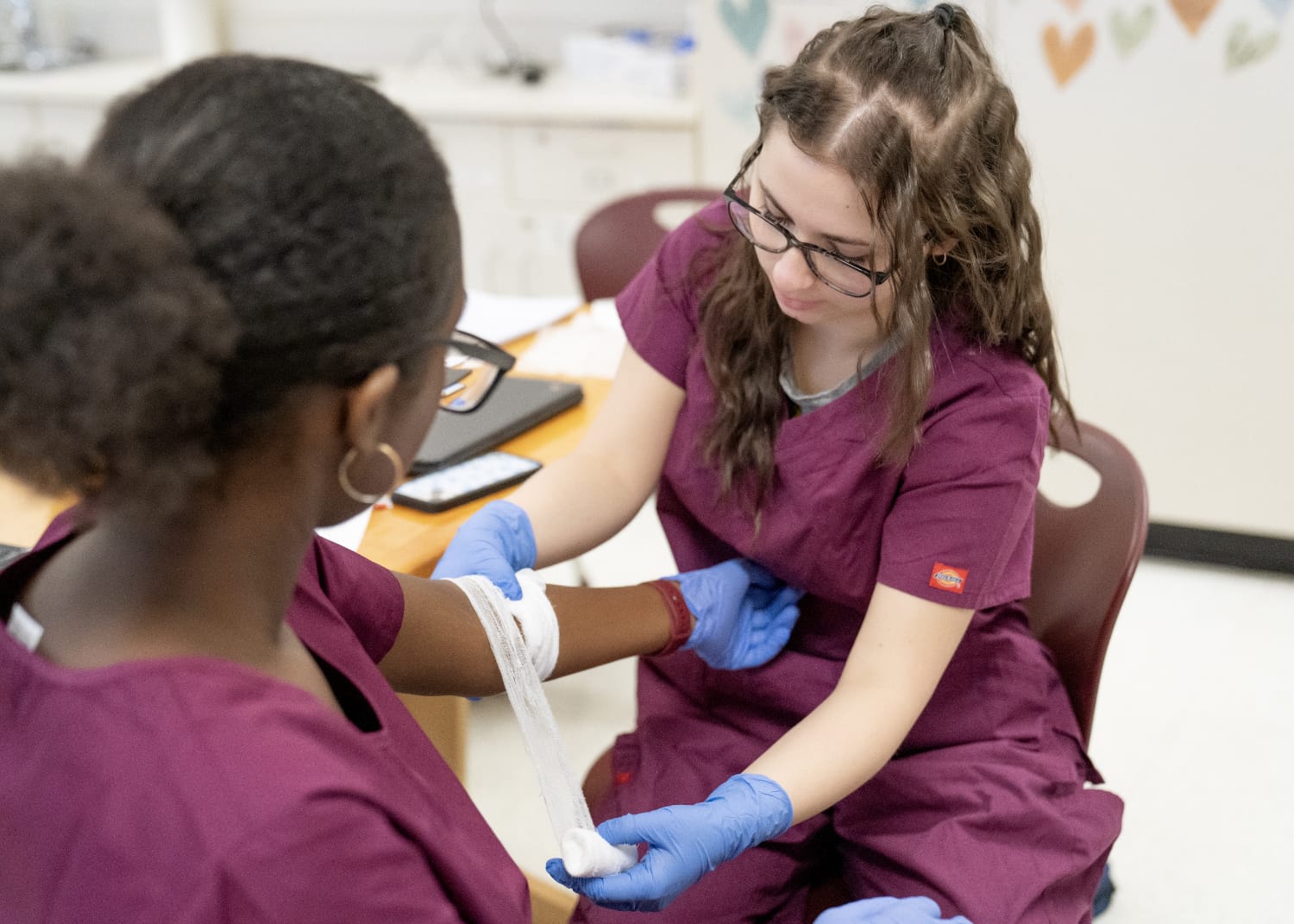 One student wrapping another's arm with medical tape