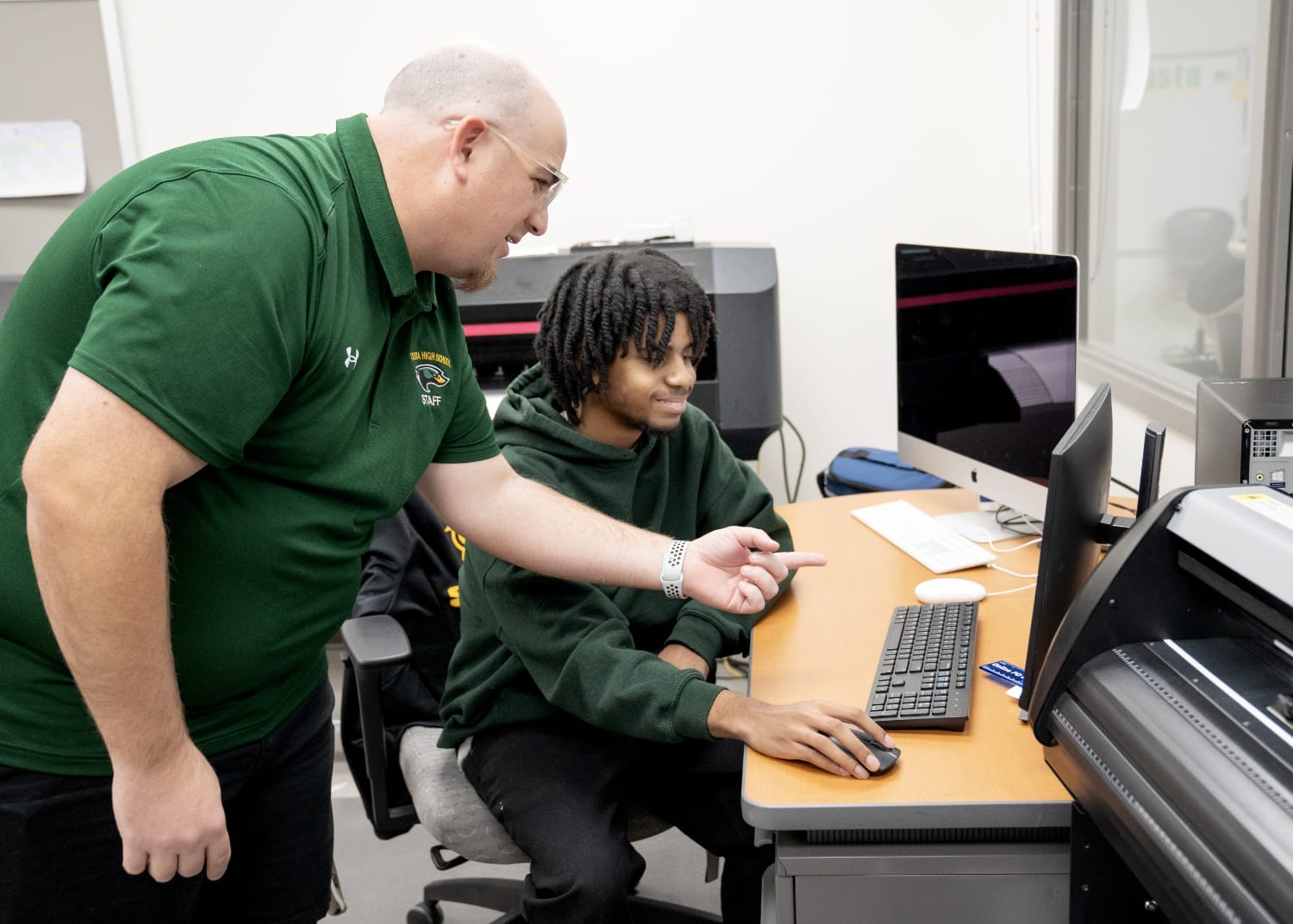 Student at a computer with teacher gesturing